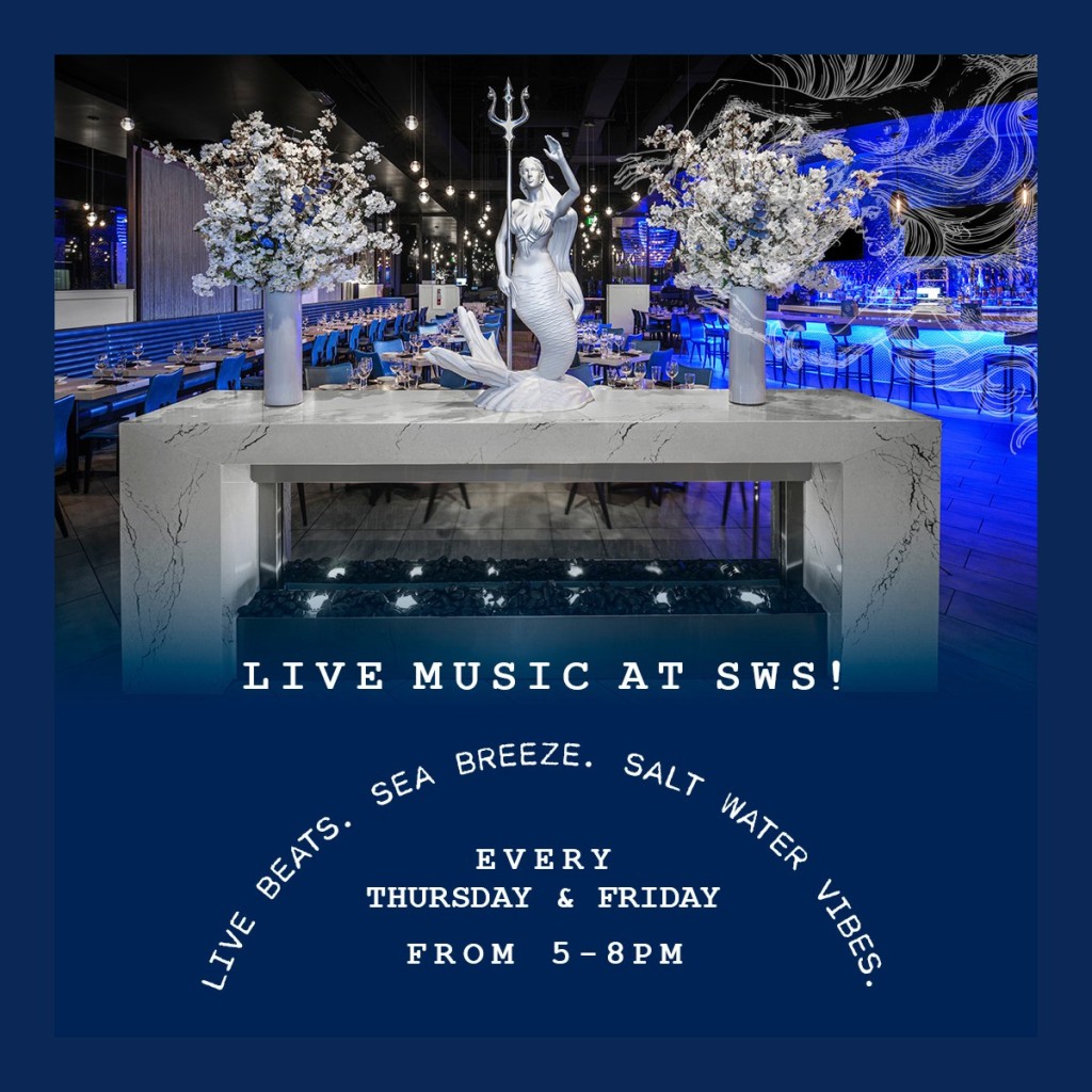 Restaurant interior featuring a white mermaid statue holding a trident, flanked by two large floral displays on a marble counter. Background shows dining and bar area. Promotional text announces 